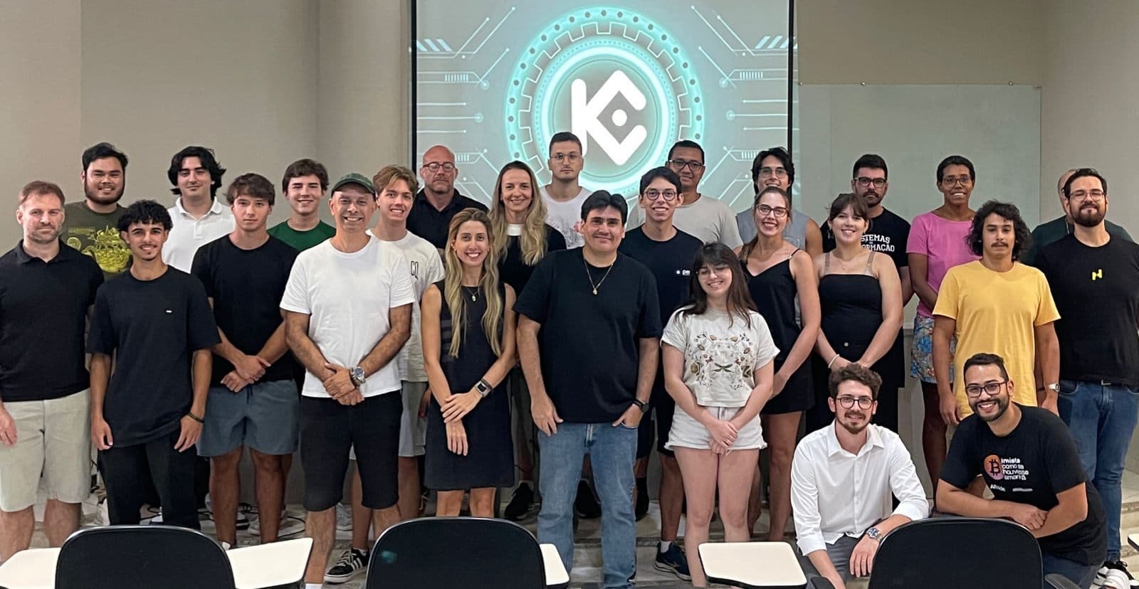 KuCoin meetup attendees in Florianópolis in front of a screen showing the KuCoin logo